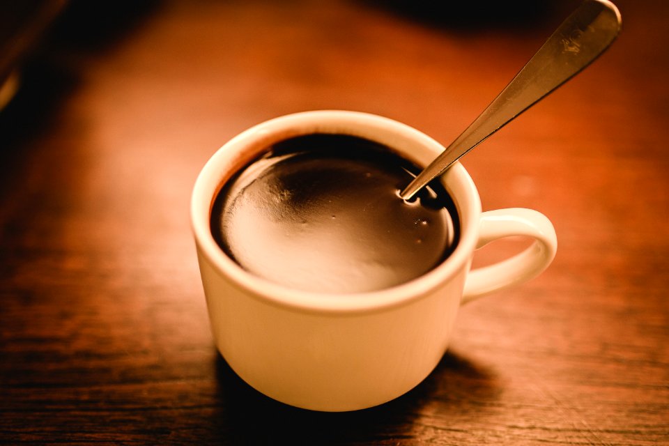 White Ceramic Espresso Cup Filled With Coffee On Brown Wooden Surface