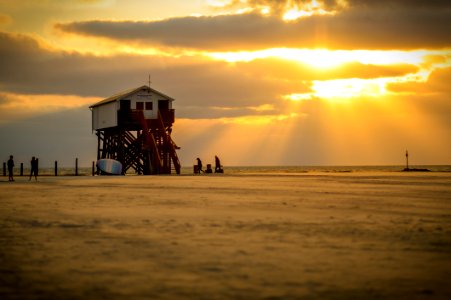 White Lifeguard House On Beach Taken Under White Clouds And Orange Sky