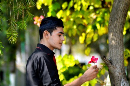 Man In Black Shirt Holding Red Petaled Flower photo