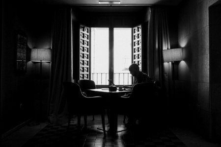 Silhouette Photography Of Man Sitting On Chair Beside Open Window photo