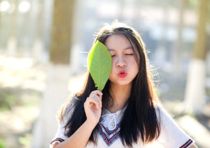 Woman Holding Green Leaf With Lips Kissing And Closing Eyes photo