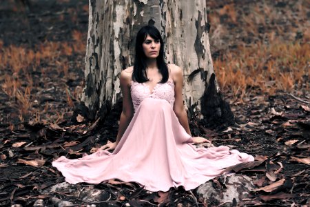 Shallow Focus Photography Of Black Haired Woman In Pink Sleeveless Dress Sitting In Front Of Tree photo