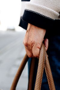 Person In White Sweater Holding Brown Handbag