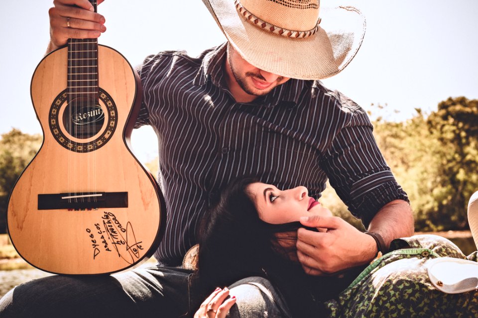 Woman In Green Top With Man In Black Long-sleeved Shirt Holding Autographed Brown Guitar photo