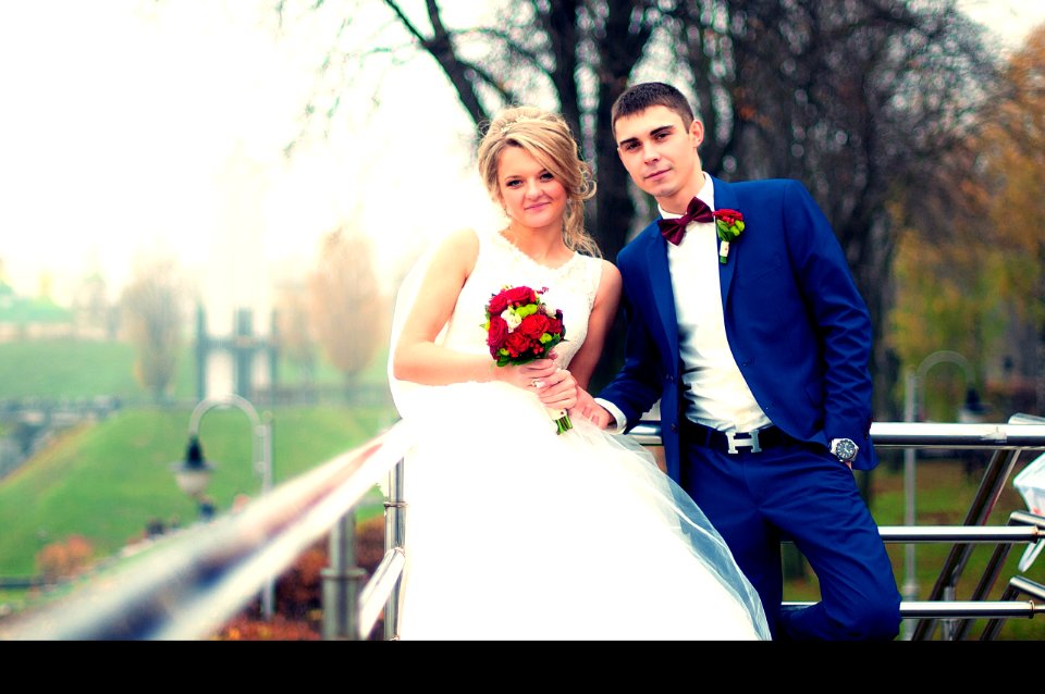 Newly Wed Couple Standing Beside Railing Near Bare Tree