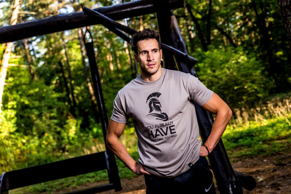 Man Wearing Brown Crew-neck T-shirt Standing Near Brown Wooden Swing At Daytime