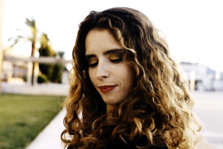Curly Brown Haired Woman Wearing Black Shirt With Red Lipstick Looking Down