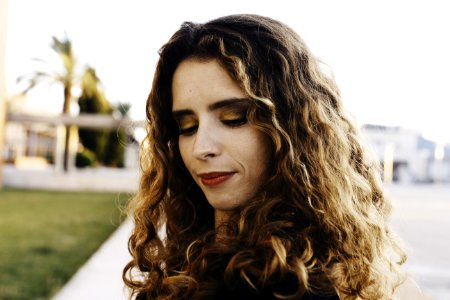 Curly Brown Haired Woman Wearing Black Shirt With Red Lipstick Looking Down photo