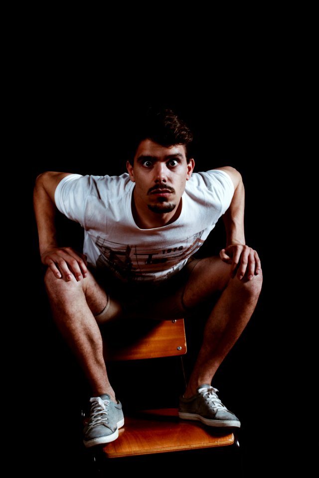 Man Wearing White Crew-neck Short-sleeved Shirt Sitting On Brown Wooden Chair photo