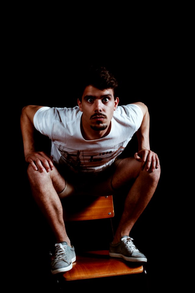Man Wearing White Crew-neck Short-sleeved Shirt Sitting On Brown Wooden Chair