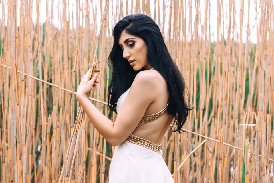Woman In White Backless Dress In Front Of Bamboo Sticks