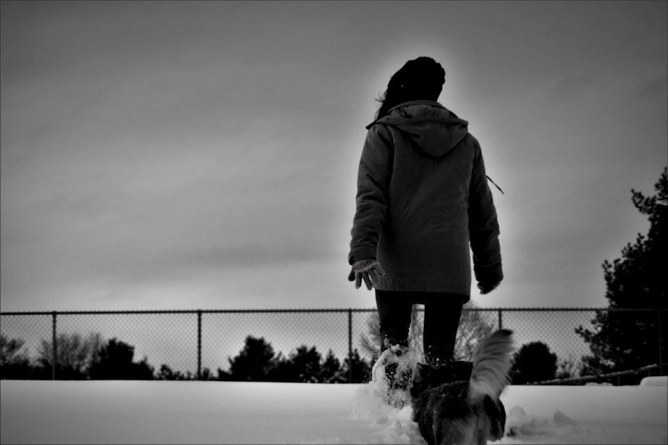 Grayscale Photo Of Person Wearing Coat Walks On Snow
