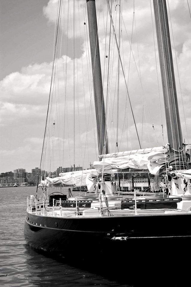 Grayscale Photo Of Ship Near High-rise Mountains