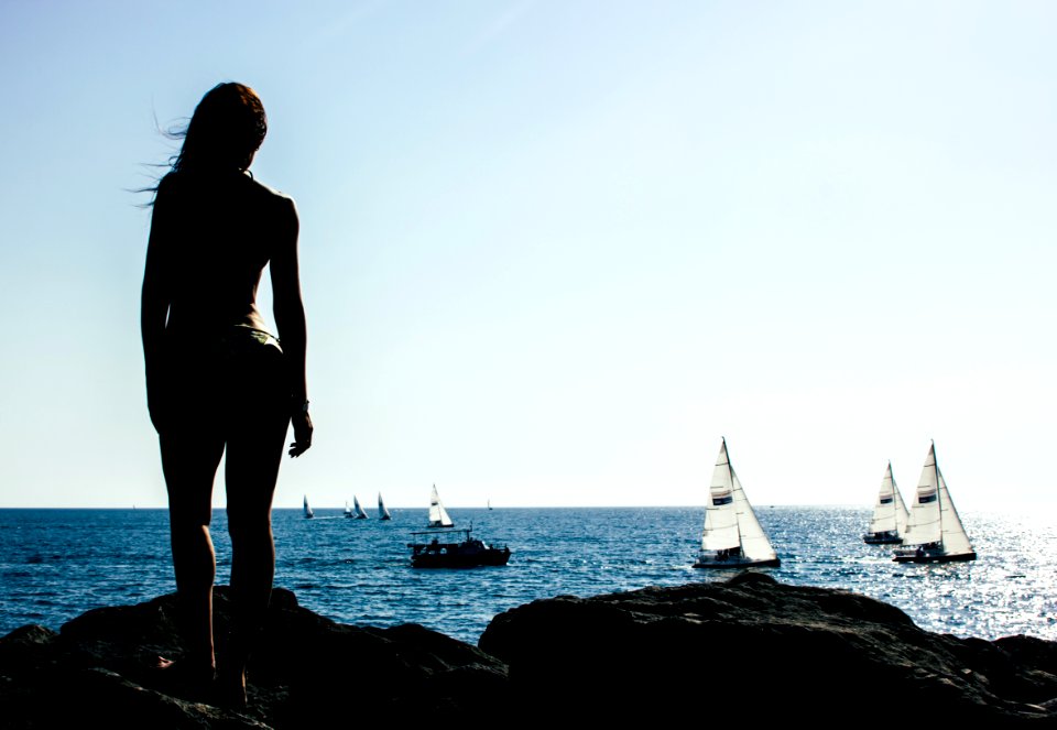 Woman Standing On Rock With Sailing Boats On Sea