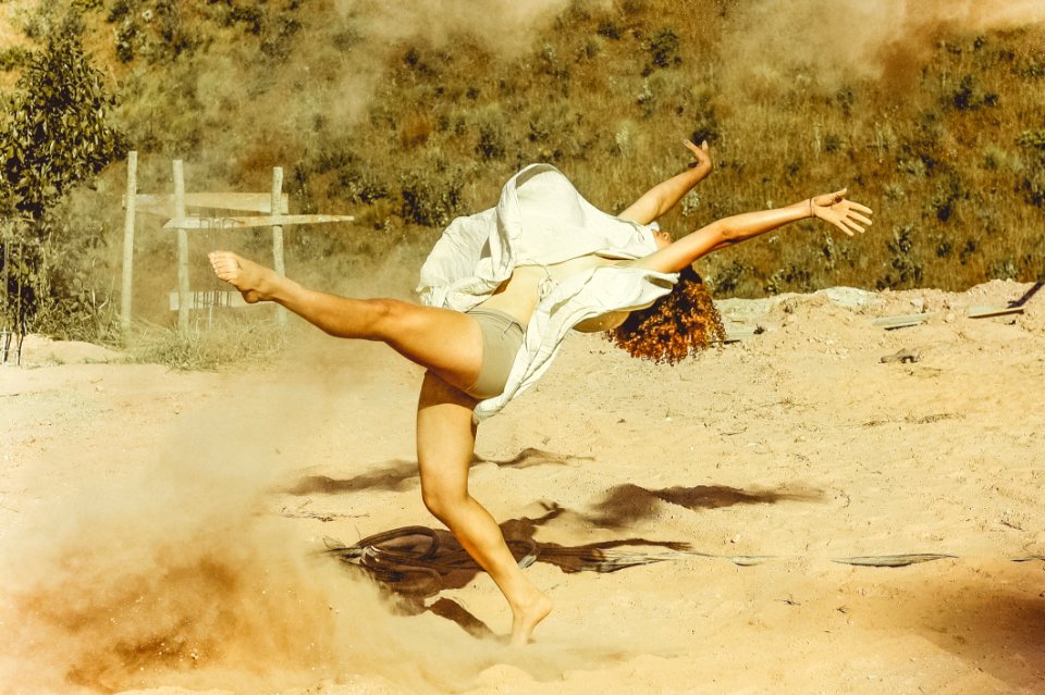 Woman Wearing White Dress Dancing On Brown Sand