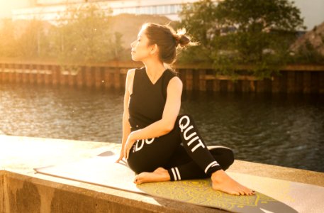 Woman Wearing Black Fitness Outfit Performs Yoga Near Body Of Water photo