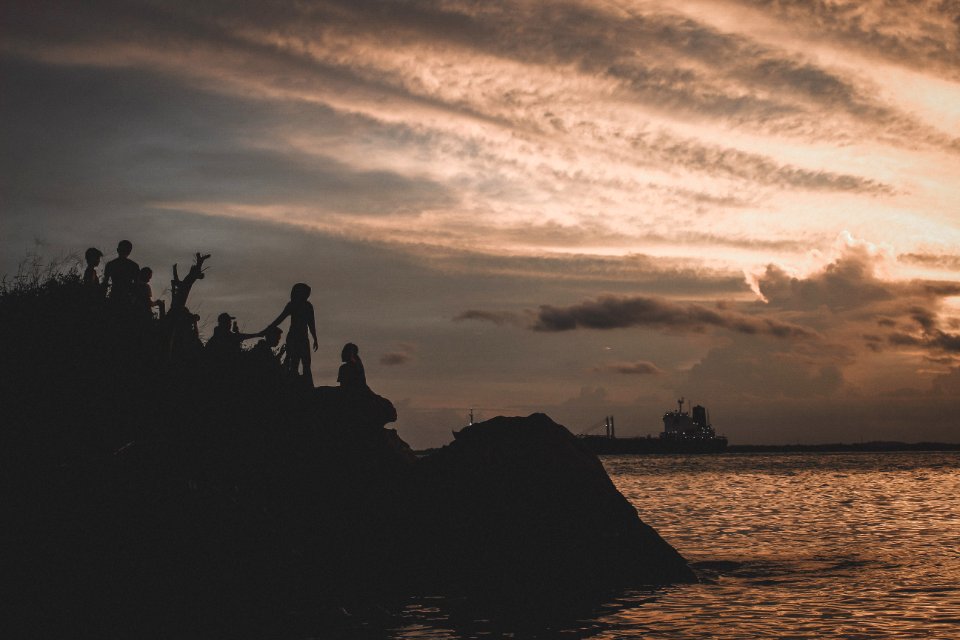 Silhouette Of People On Mountain Near Body Of Water