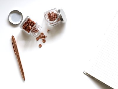 Bunch Of Thumbtacks With Two Clear Glass Containers On White Surface