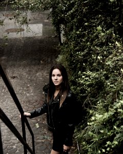 Close Up Photograph Of Woman With Black Leather Jacket Standing Beside Stair Handle