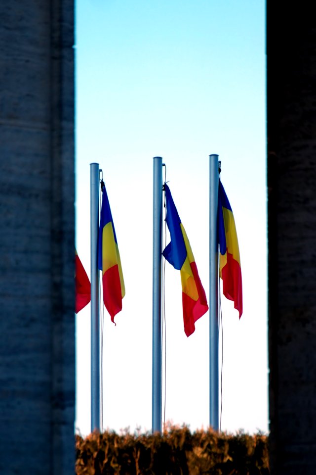 Three Blue-yellow-and-red Flags On Gray Pole
