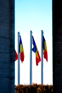 Three Blue-yellow-and-red Flags On Gray Pole photo