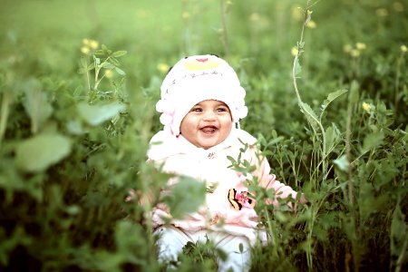 Toddler Wearing Whit Cap On Green Field photo