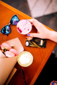 Woman Holding Beverage Filled Cup Near Sunglasses And Phone photo