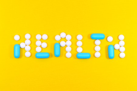 White And Blue Health Pill And Tablet Letter Cutout On Yellow Surface photo