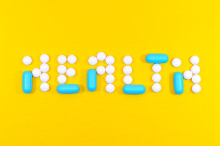 White And Blue Health Pill And Tablet Letter Cutout On Yellow Surface