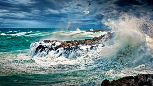 Beach Beside Stone Formation With Waves At Daytime photo