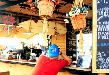 Man Near Counter Desk With Hanging Surfboard photo