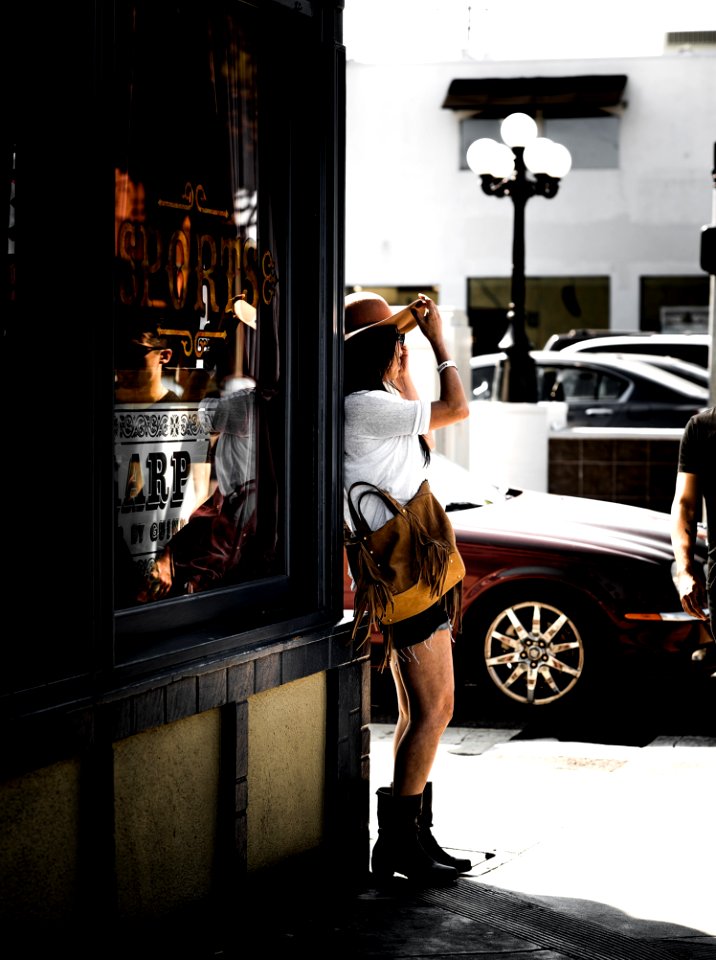 Woman In Brown Sunhat Standing On Sidewalk