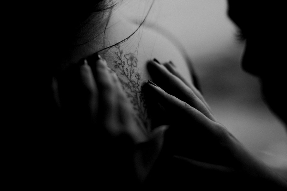 Grayscale Photo Of Man Looking At Womans Back Flower Tattoo