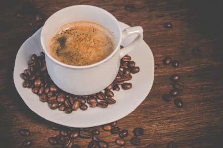 A Cup Of Coffee On Brown Wooden Table With Coffee Seeds photo