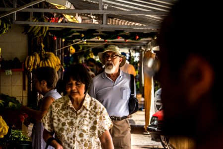 Man In Purple Polo Shirt And Brown Hat Behind Woman In Brown And White Floral Button-up T-shirt