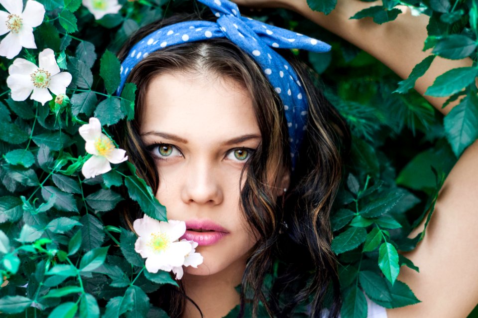 Portrait Photo Of Woman In White Top And Blue Polka Dot Headband Near Flowers