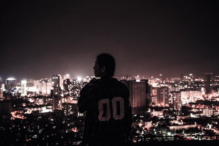 Photography Of A Person Watching Over City Lights During Night Time photo