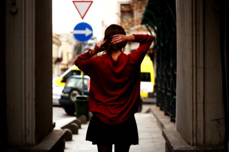 Woman In Red Sweater And Black Miniskirt Holding Hair Facing Road photo