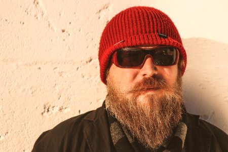 Bearded Man Wearing Red Beanie Cap Sunglasses and Black Jacket photo