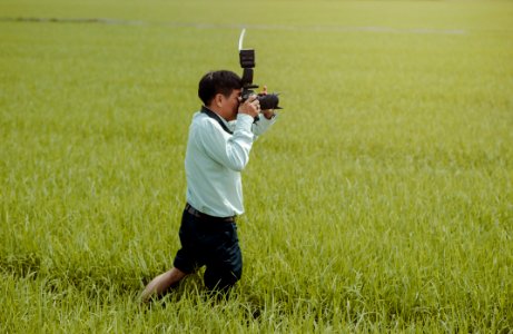 Man Standing On Rice Field Holding Camera photo