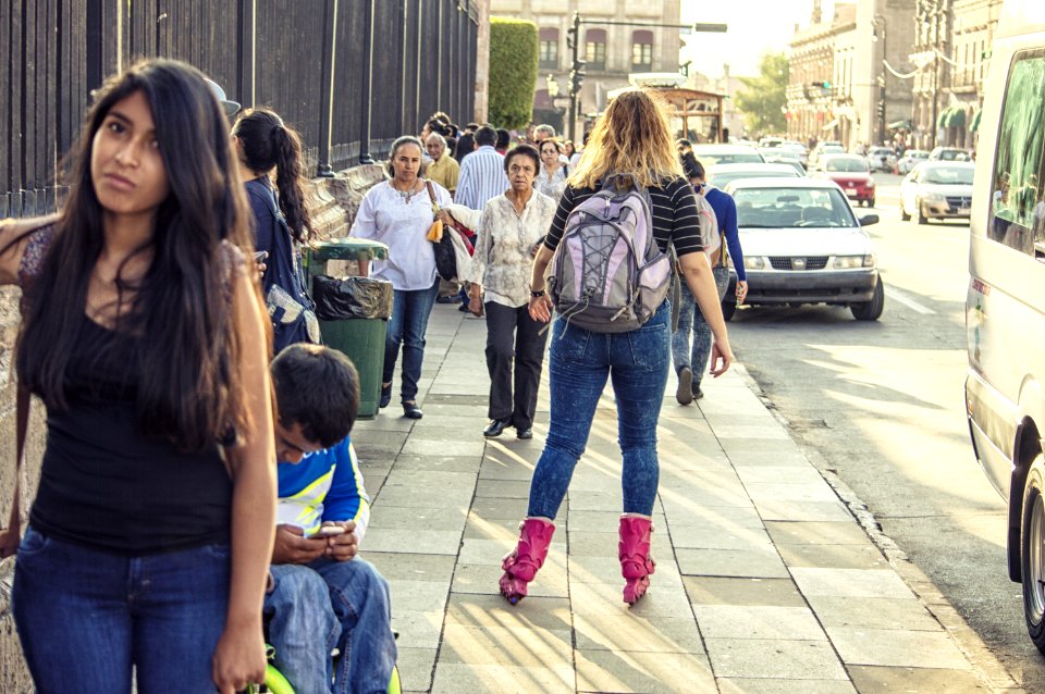 Woman In Black T-shirt Blue Washed Denim Jeans And Pair Of Pink Inline Skates Skating In Street
