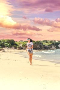 Smiling Woman Walking Barefood On Seashore Near Houses