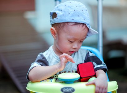 Boy In Gray Crew-neck Shirt Wearing Gray Cap Riding On Yellow And Blue Walker photo