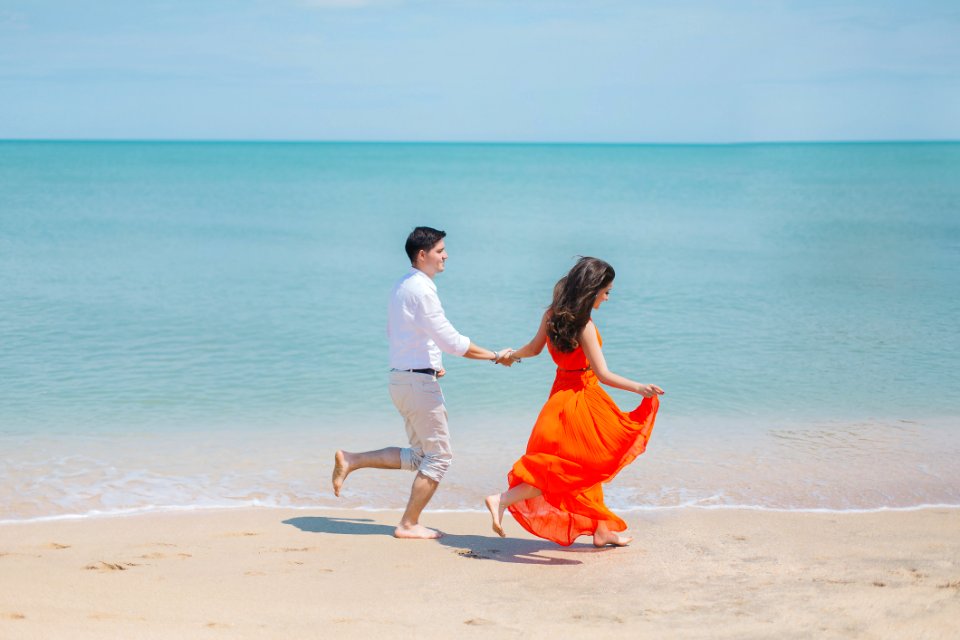 Man And Woman Walks Beside Green Sea photo