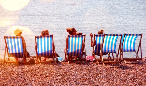 Four People On Lounge Chairs Near The Beach