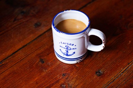White And Blue Sailor Ceramic Coffee Mug On Brown Wooden Surface photo