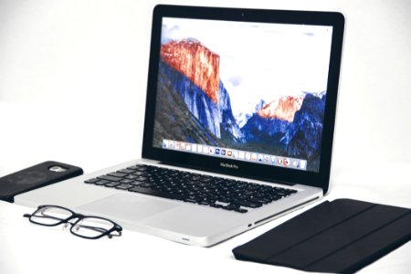 Macbook Air Beside Eyeglasses And Black Smart Case photo