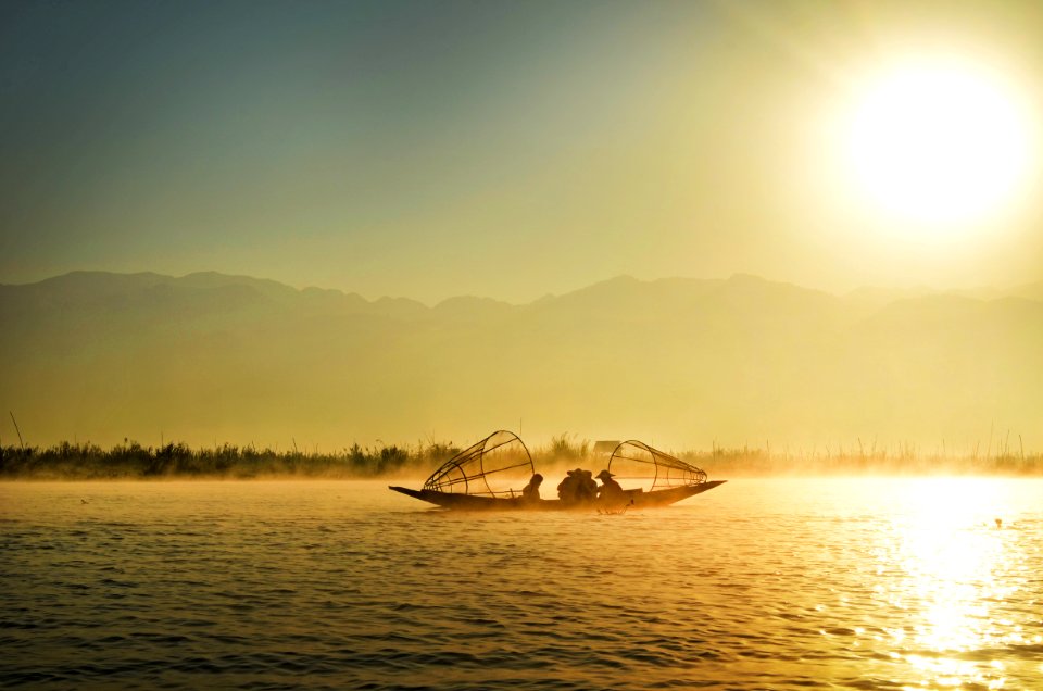 Group Of People Riding Boat In The Middle Of Water During Sunrise