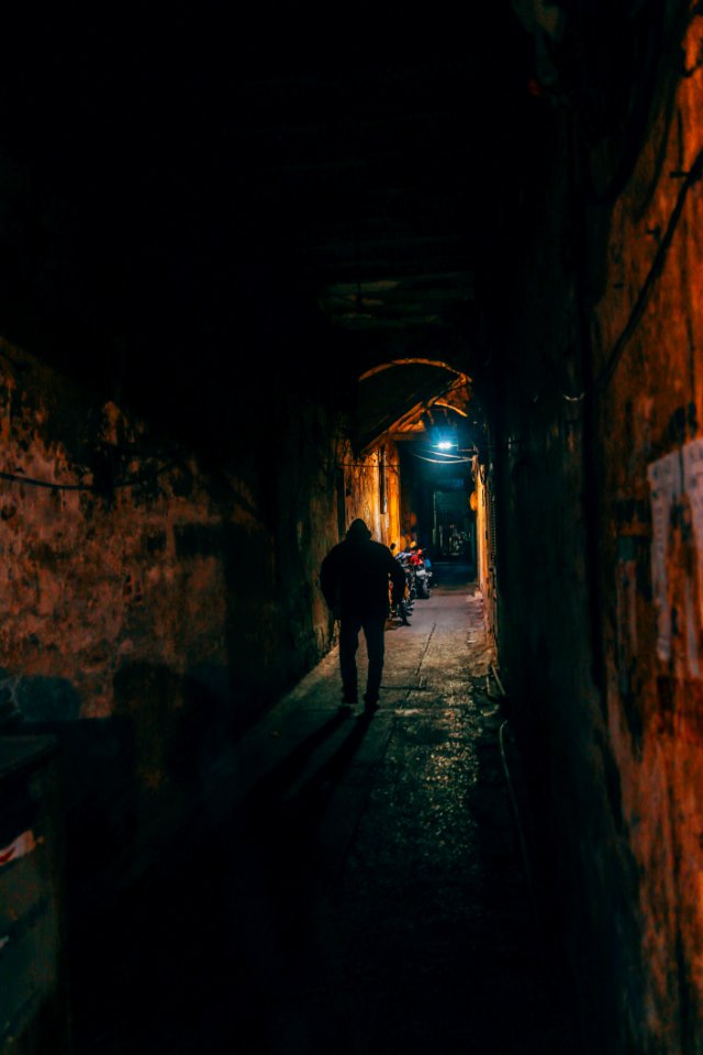 Photo Of Person Walking Along Brown Wall Tunnel
