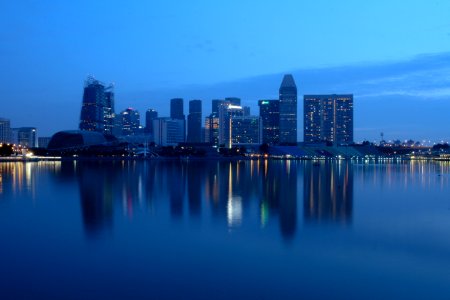 City Buildings Beside Body Of Water During Night Time photo